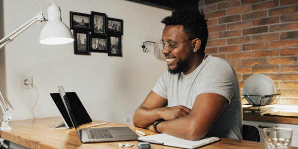 man smiling after looking at his higher credit score on his laptop