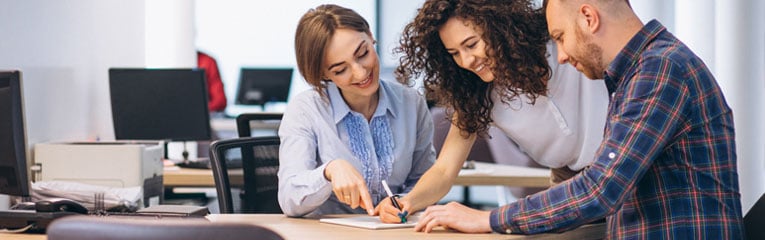 Three-business-owners-decide-if-they-want-to-buy-commercial-property-for-their-business-by-reviewing-paperwork-together.