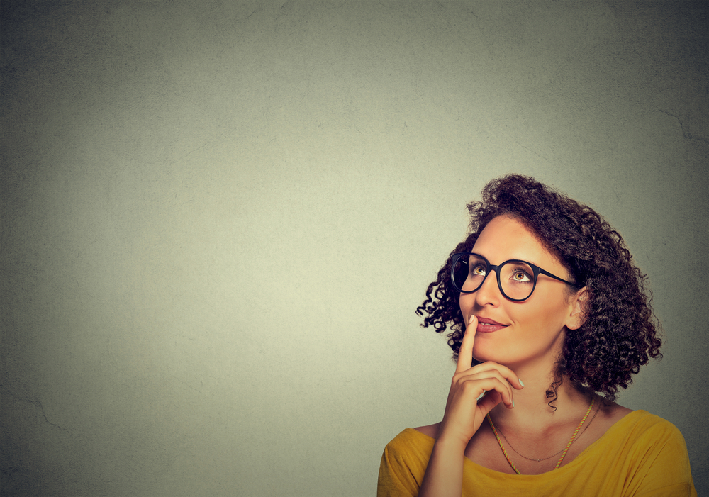 Portrait side profile happy beautiful woman thinking looking up isolated on grey wall background with copy space. Human face expressions, emotions, feelings, body language, perception