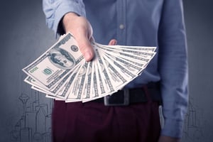 Young businessman holding large amount of bills with grungy drawings of a city and numbers behind him